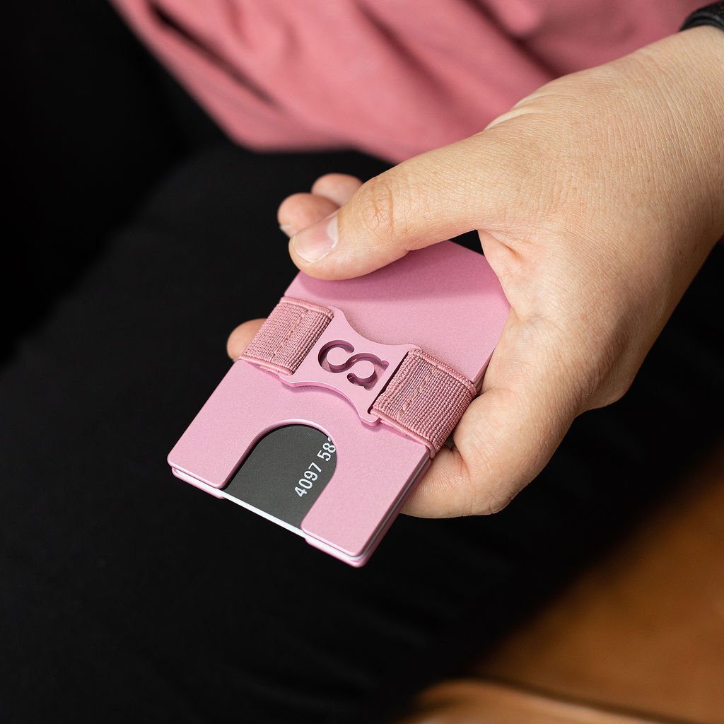 a person holding a pink cell phone in their hand 